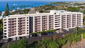 A multi-story hotel with a parking lot and ocean view. - Big Island Kailua Village 208 1 Bedroom Condo (Kailua-Kona)