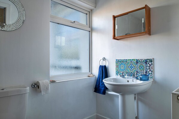 Une salle de bain avec des toilettes, un lavabo, un miroir et une fenêtre.