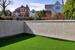 Stunning corner garden with a neatly trimmed lawn and low stone wall, surrounded by unique houses with distinct architectural styles.
