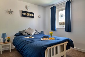 Enjoy a peaceful retreat with a well-appointed bedroom featuring a comfortable bed, bedside table, and a potted plant.