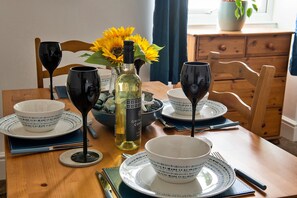 A dining table set for a meal, featuring a variety of tableware and glassware, accompanied by a chair and a cabinet.