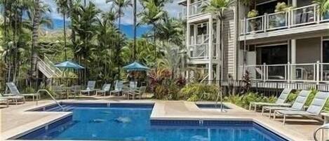 A pool area with lounge chairs and palm trees.