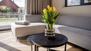 Una sala de estar moderna con un sofá gris, una mesa de centro negra y un jarrón con flores amarillas.