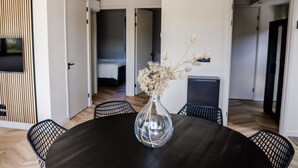 Un comedor con una mesa redonda, sillas y un jarrón con flores secas.