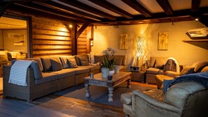 Una sala de estar acogedora con techo de madera, un conjunto de sofá, una mesa de centro con adornos y una chimenea.