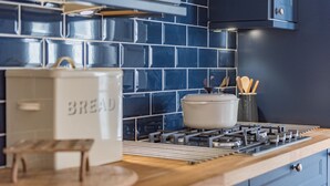 A kitchen with a stove, a bread box, and a pot on the counter.