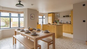 Eine moderne Küche mit Holztisch, gedecktem Esstisch, einem großen Fenster und Blick nach draußen.