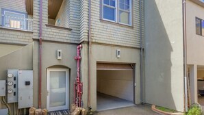 A residential building with a garage, a door, and utility meters.