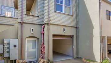 A residential building with a garage, a door, and utility meters.
