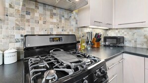 A kitchen with a gas stove, a microwave, and a tiled backsplash.