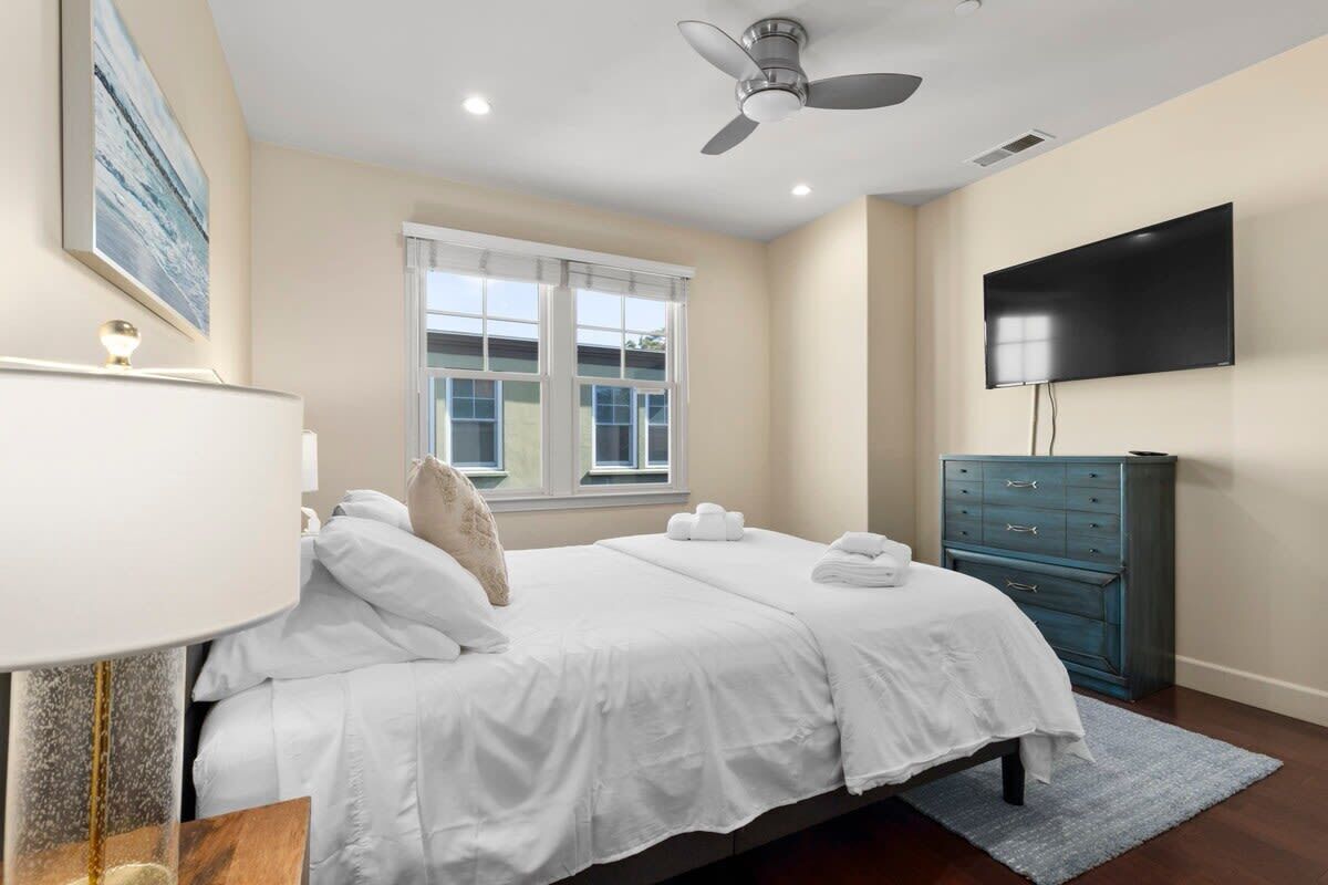 Une chambre d’hôtel équipée d’un lit, d’un ventilateur de plafond, d’un téléviseur à écran plat, d’une commode et d’une fenêtre avec des stores.