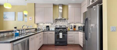 A modern kitchen with stainless steel appliances, light-colored cabinets, and a tiled backsplash.