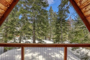 A view from a wooden balcony overlooking a forested area with snow on the ground. - Rustic & Modern 3BDR Tahoe Cabin (Tahoe City)