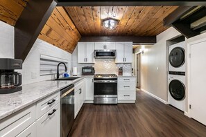 Eine moderne Küche mit weißen Schränken, Edelstahlgeräten und einer Holzbalkendecke.