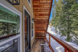 A wooden balcony with a metal railing, a glass door, and a view of a snowy landscape with trees. - Rustic & Modern 3BDR Tahoe Cabin (Tahoe City)