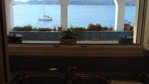 Cozinha com vista para um lago e montanhas através de janelas em arco.