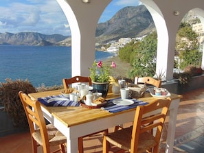 A table set for breakfast with a view of the sea and mountains.
