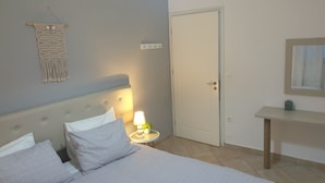 Quarto com cama, abajur e um pendente de macramé na parede.