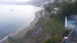 Uma praia com pessoas tomando sol e um barco na água.