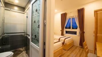 A bathroom with a glass shower enclosure, a toilet, and a vanity.