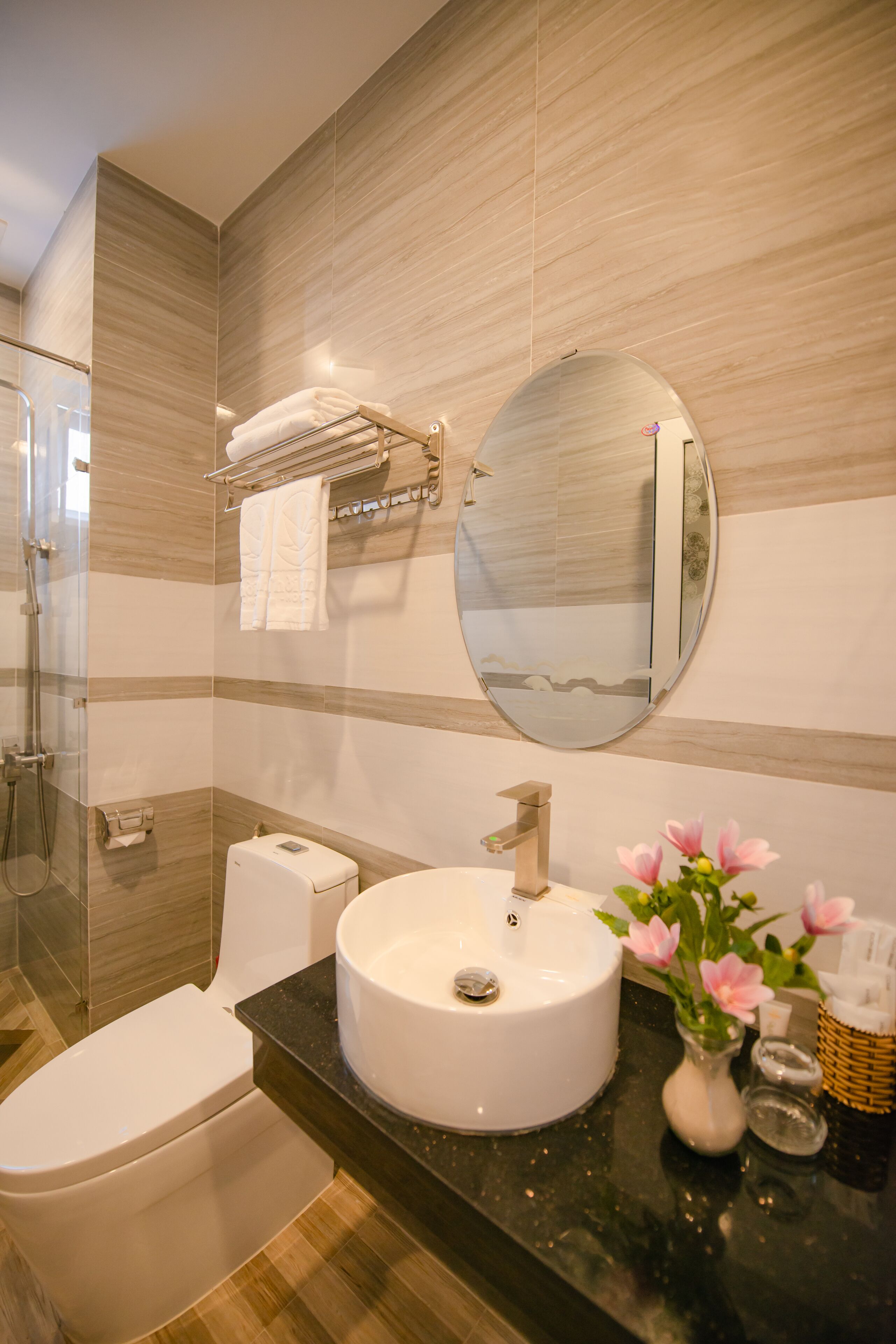 Un baño moderno con un espejo redondo, un lavamanos blanco y un inodoro.