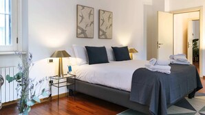 Un dormitorio ordenado con cama, lámparas de noche, mesita de noche y ventana.