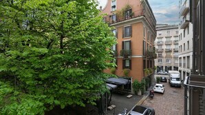 Una calle urbana estrecha con coches aparcados y un callejón arbolado.