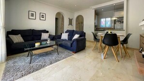 A modern living room with a sofa, coffee table, and dining area. - South facing Los Dolses bungalow - comm pool LD186 (Los Dolses)