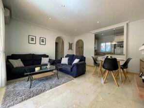 Een moderne woonkamer met een bank, salontafel en eethoek.