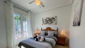 A bedroom with a bed, two bedside tables, a ceiling fan, and artwork on the walls. - South facing Los Dolses bungalow - comm pool LD186 (Los Dolses)