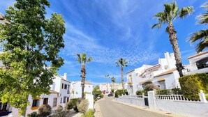 A residential street with white houses, palm trees, and a clear blue sky. - South facing Los Dolses bungalow - comm pool LD186 (Los Dolses)