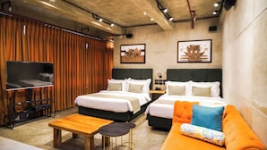 A hotel room with two beds, a sofa, a TV, and a wooden table. - Aqua Frontier Hotel and Restaurant (Lobo)