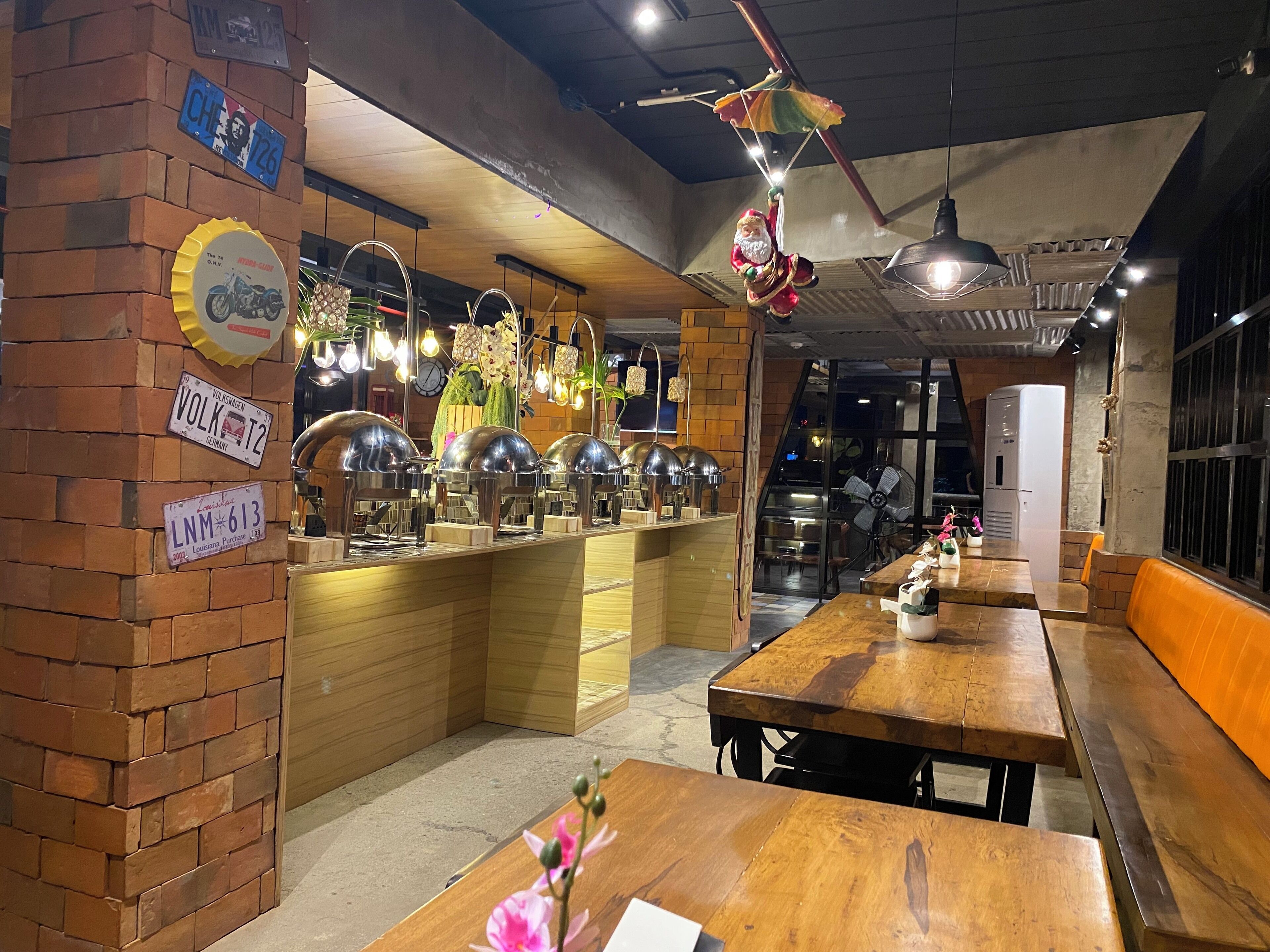 Interior de restaurante con paredes de ladrillo, mesas de madera y lámparas colgantes.