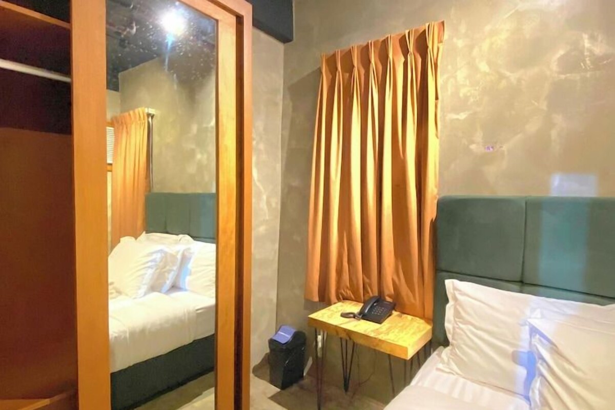A hotel room with a bed, a desk with a telephone, and a wardrobe.
