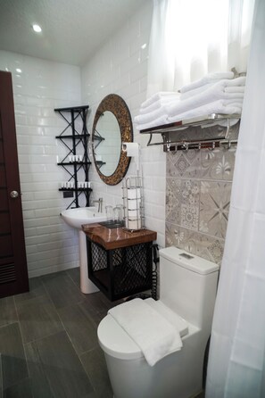 A modern bathroom with a white sink, a wooden vanity, a toilet, and a shower area with a decorative shower curtain. - Aqua Frontier Hotel and Restaurant (Lobo)