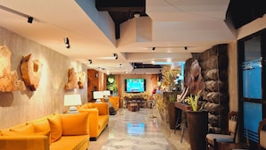 A spacious lobby with a marble floor, a yellow sofa, a stone wall, and a television screen. - Aqua Frontier Hotel and Restaurant (Lobo)
