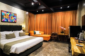 A modern hotel room with a large bed, a sofa, a desk, and a television. - Aqua Frontier Hotel and Restaurant (Lobo)