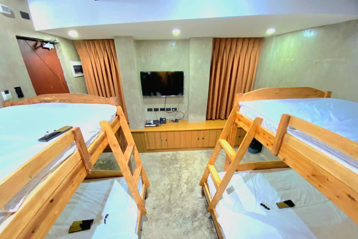 A room with bunk beds, a television, wooden cabinets, and a small table.