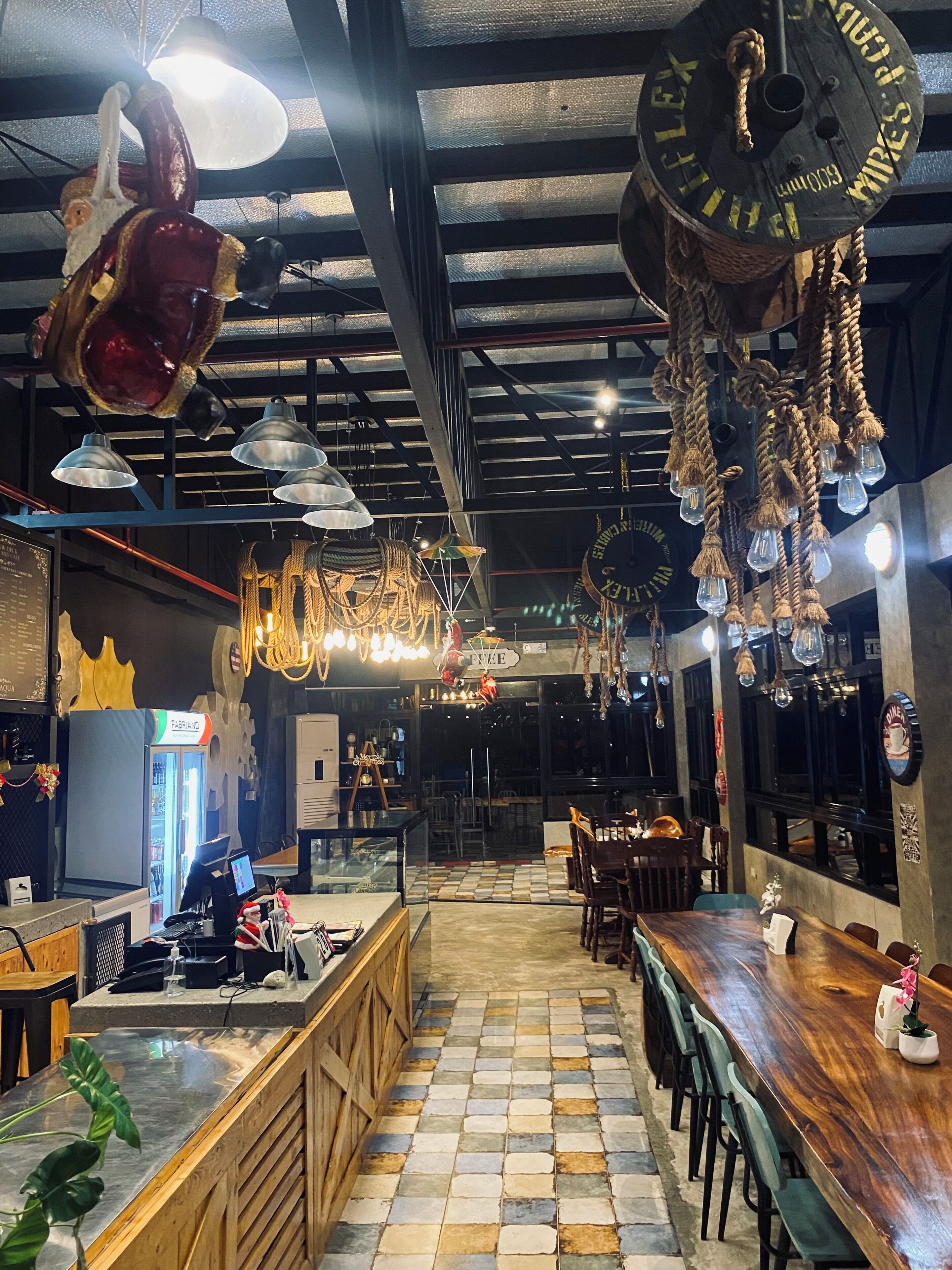 A restaurant interior with a check-in counter, seating area, and hanging light fixtures.