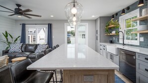 A modern kitchen with a central island, built-in appliances, and a dining area with a leather couch and chairs. - 409 Paynter Avenue - In town Lewes with a private pool! (Lewes)