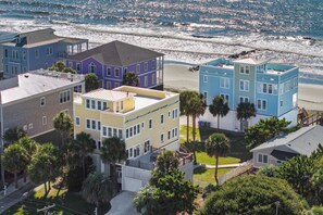 A coastal residential area with colorful houses, a beach, and palm trees.