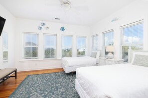 A bedroom with a large bed, a smaller bed, a bench, and a window with blinds.