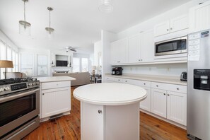 A modern kitchen with white cabinetry, a central island, stainless steel appliances, and a ceiling fan.