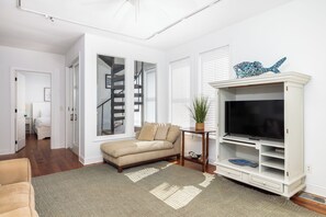 A living room with a sofa, TV stand, and a staircase.