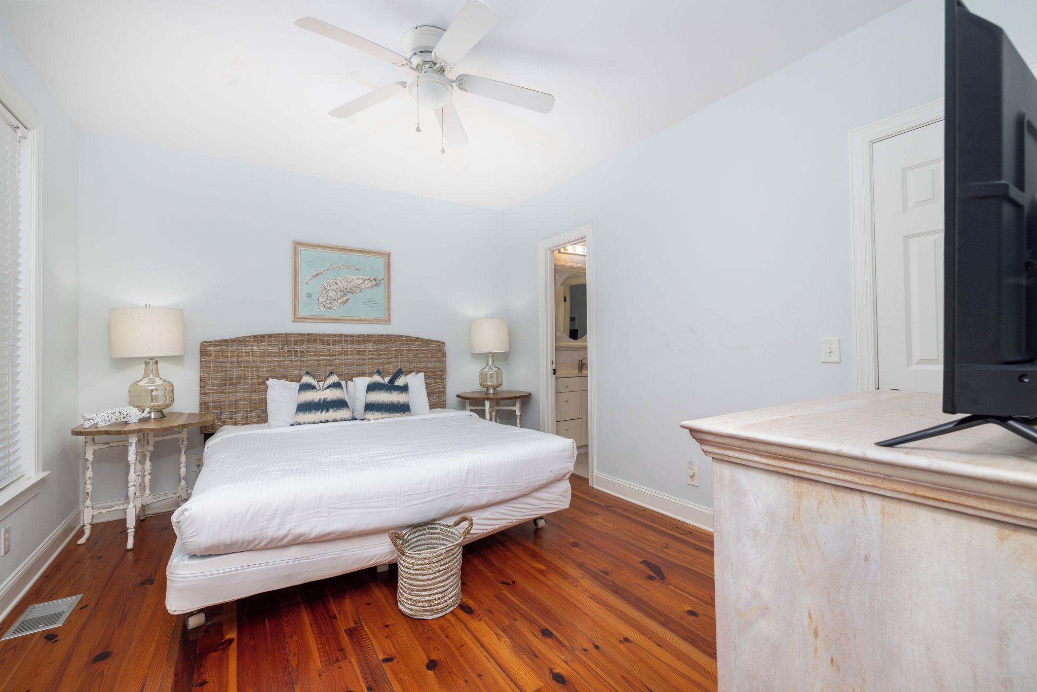 Une chambre à coucher avec un lit, un ventilateur de plafond, un téléviseur et une carte encadrée accrochée au mur.