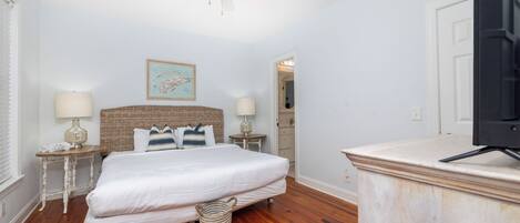 Une chambre à coucher avec un lit, un ventilateur de plafond, un téléviseur et une carte encadrée accrochée au mur.