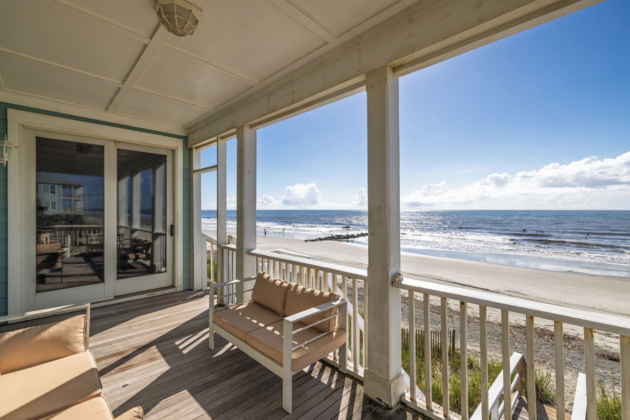 A wooden deck with a bench and a view of the beach.