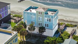 Un edificio de varios pisos con piscina en la azotea y vista al mar.