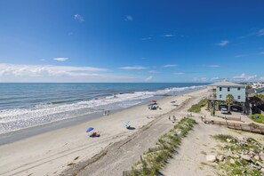 A beach with a building on the right, a clear sky, and the ocean. - Stunning 4-Bedroom Oceanfront Home with Rooftop Deck and 360-Degree Views (Folly Beach)