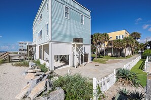 A beachfront property with a multi-level building, a wooden deck, and a paved walkway.